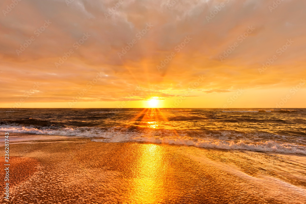 scenic sunset over sea with setting sun rays coming through dramatic clouds on orange blue sky reflecting on water panoramic aerial nature dusk atmosphere evening landscape background