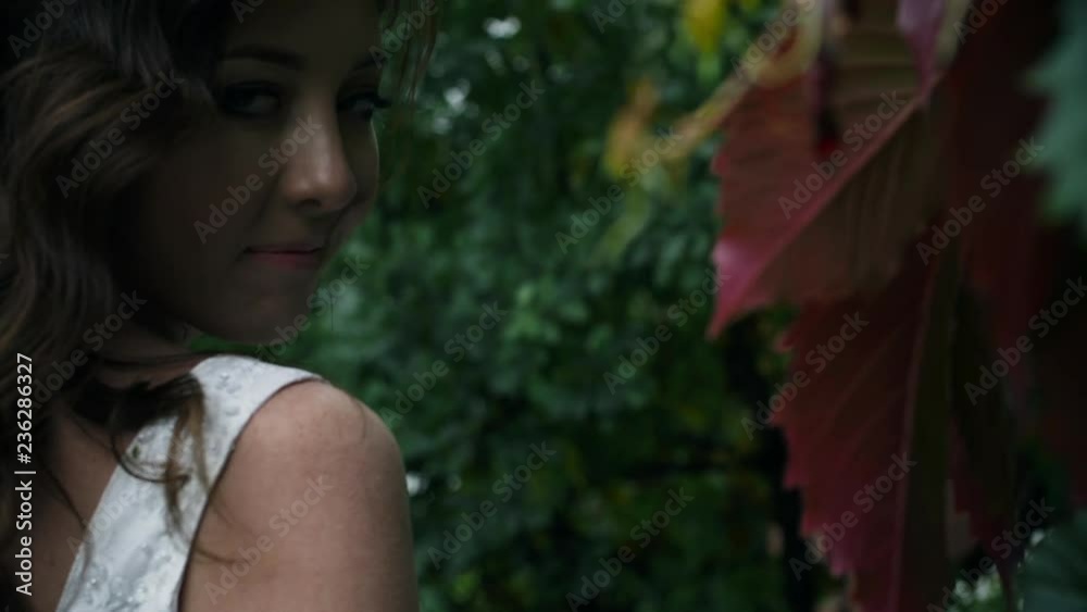 Beautiful girl smiles and touches hand of green leaves Beautiful girl smiles and touches hand of green leaves