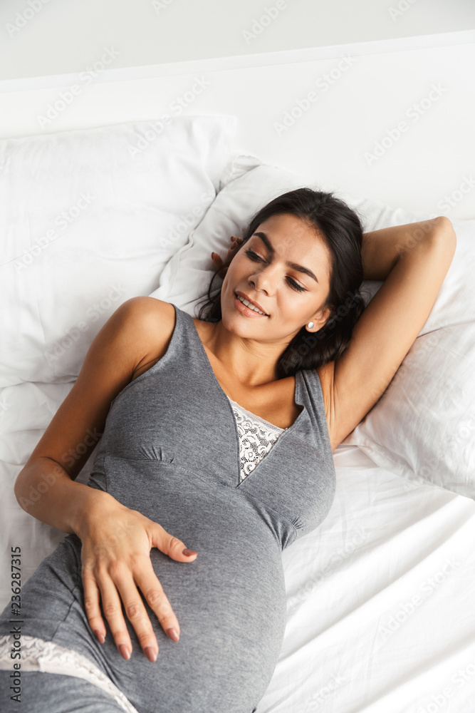 Pregnant woman indoors at home lies in bed. Pregnant woman indoors at home lies in bed.