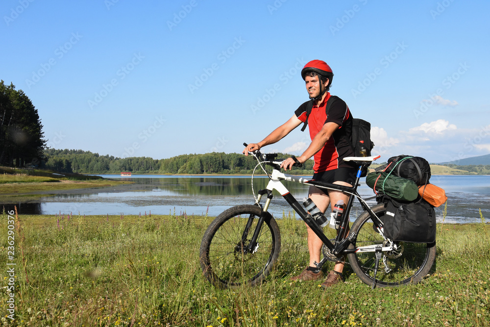 Cyclist with a saddle bag near a lake. Traveler on bicycle on sunny day Cyclist with a saddle bag near a lake. Traveler on bicycle on sunny day