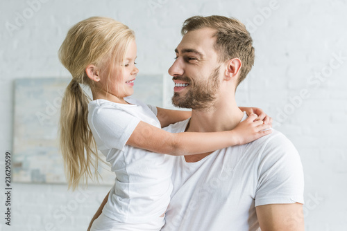 happy father and cute little daughter hugging and smiling each other at home