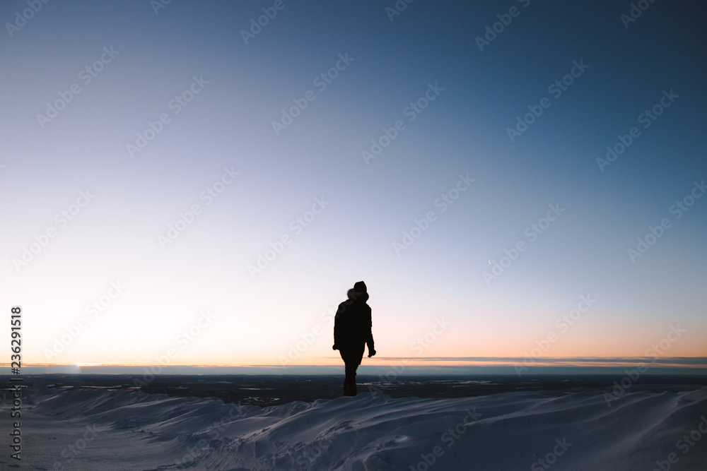 man walking on snow at sunset / sunrise