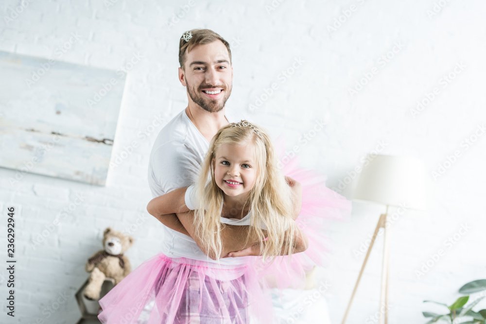 Fototapeta premium happy father and adorable little daughter in pink tutu skirts dancing and smiling at camera