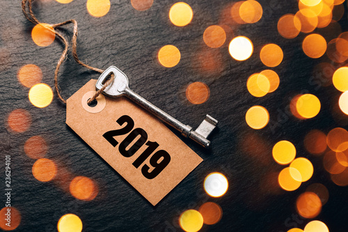 Metal key with 2019 year tag. Festive picture with lightening golden bokeh lights. photo