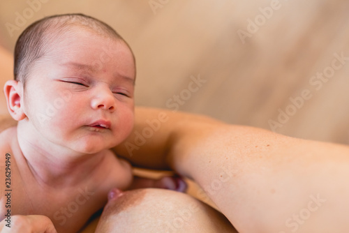 Newborn baby resting after breastfeed and feeding on his mother breast