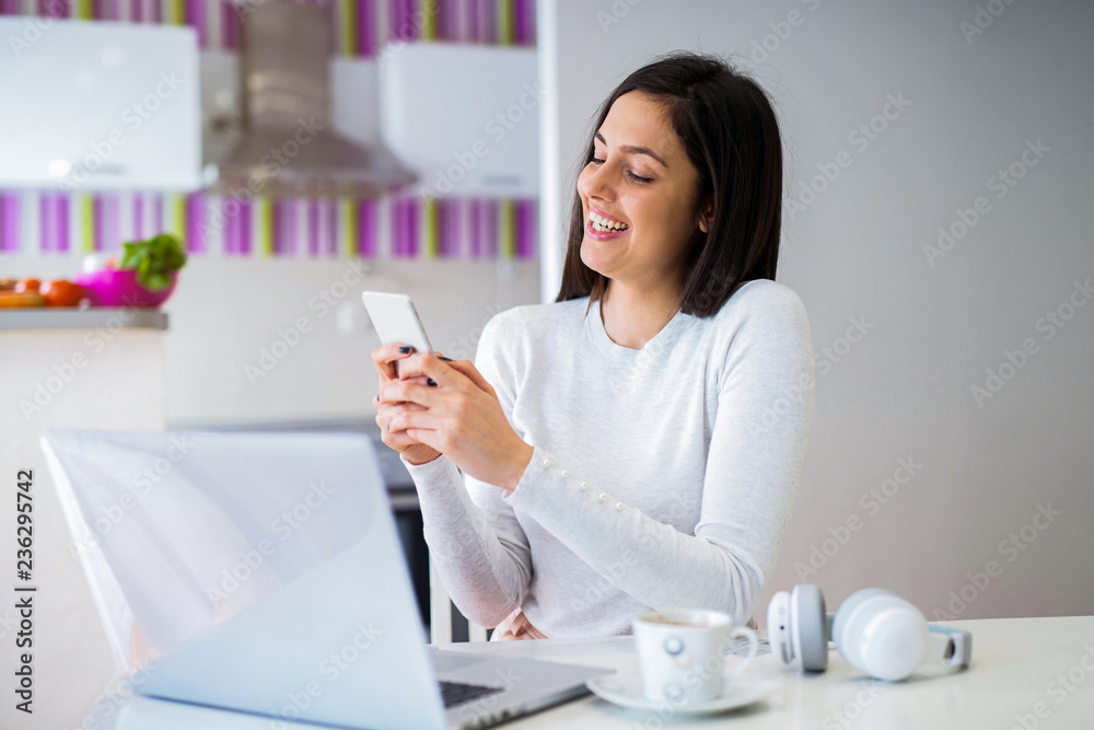 Young student girl taking break from studding and sitting in front of computer and holding telephone in her hands. Young student girl taking break from studding and sitting in front of computer and holding telephone in her hands.