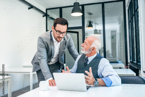 Cuadro en lienzo Young man discussing with boss or older employee in modern office
