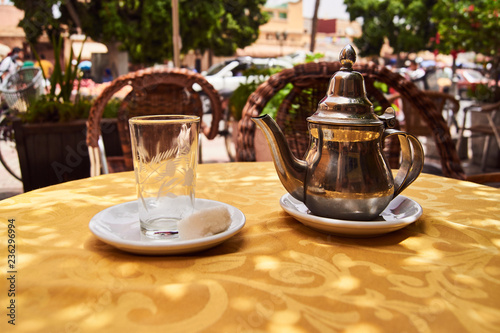 A glass and a traditional tea pot on a table in Morocco.