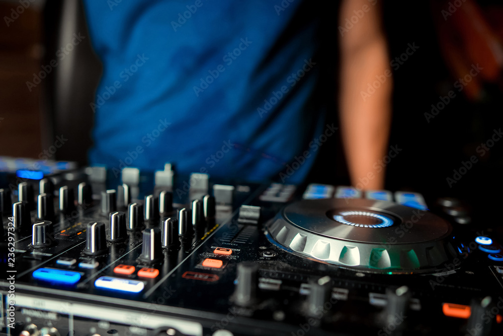 Obraz premium Dj mixes the track in the nightclub at party. In the background laser light show