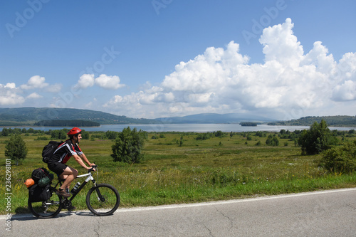 Cyclist with a saddle bag near a lake. Traveler on bicycle on sunny day