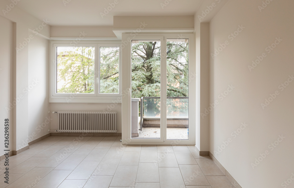 Empty room with radiators and large windows overlooking nature - obrazy, fototapety, plakaty 