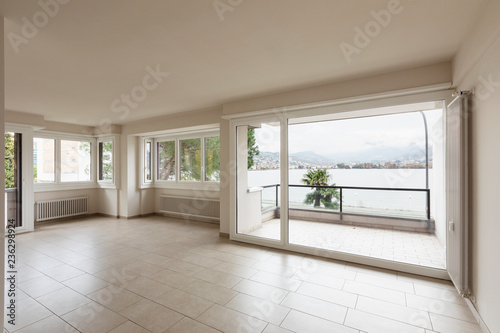 Empty room with radiators and large window overlooking Lake Lugano