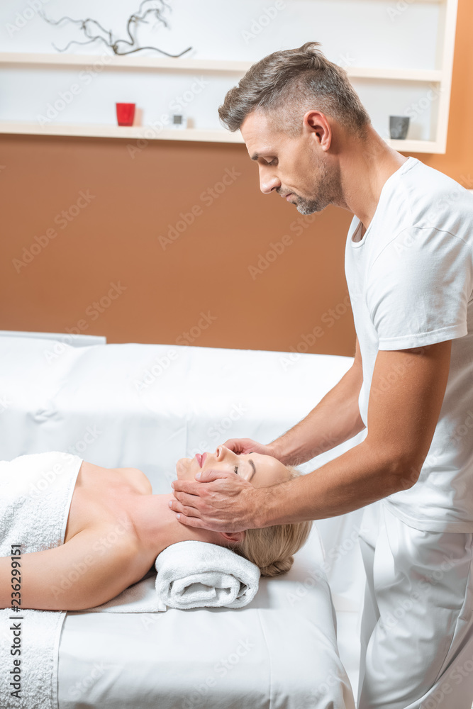 Fototapeta premium Male masseur doing face massage in spa salon