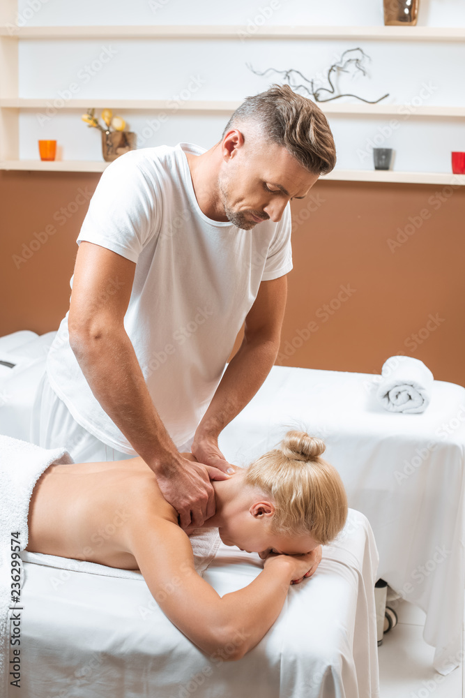 handsome masseur doing neck massage to blonde woman handsome masseur doing neck massage to blonde woman
