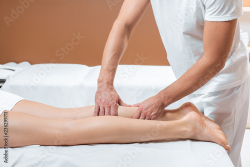cropped view of man massaging woman legs in spa