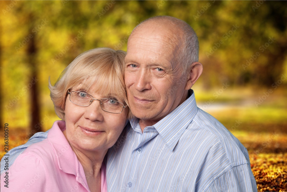 Close-up portrait of an elderly couple hugging in park Close-up portrait of an elderly couple hugging in park