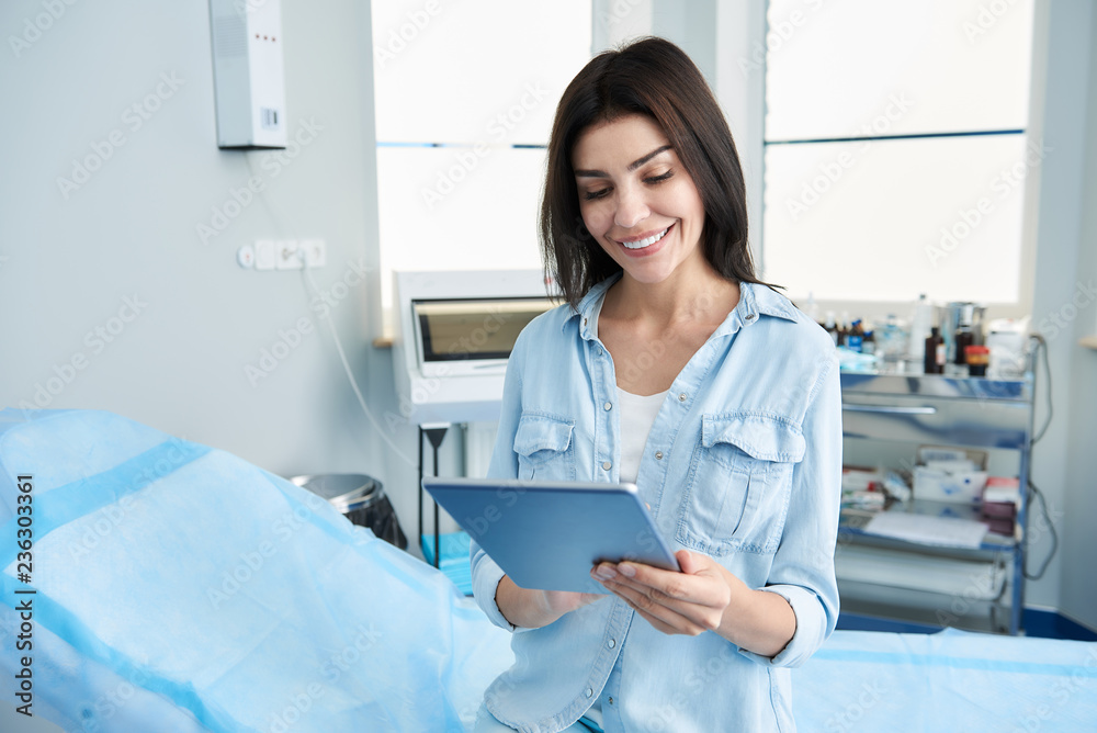 Waist up photo of pretty lady holding tablet in her hands and filling out questionnaires. Copy space on left side Waist up photo of pretty lady holding tablet in her hands and filling out questionnaires. Copy space on left side