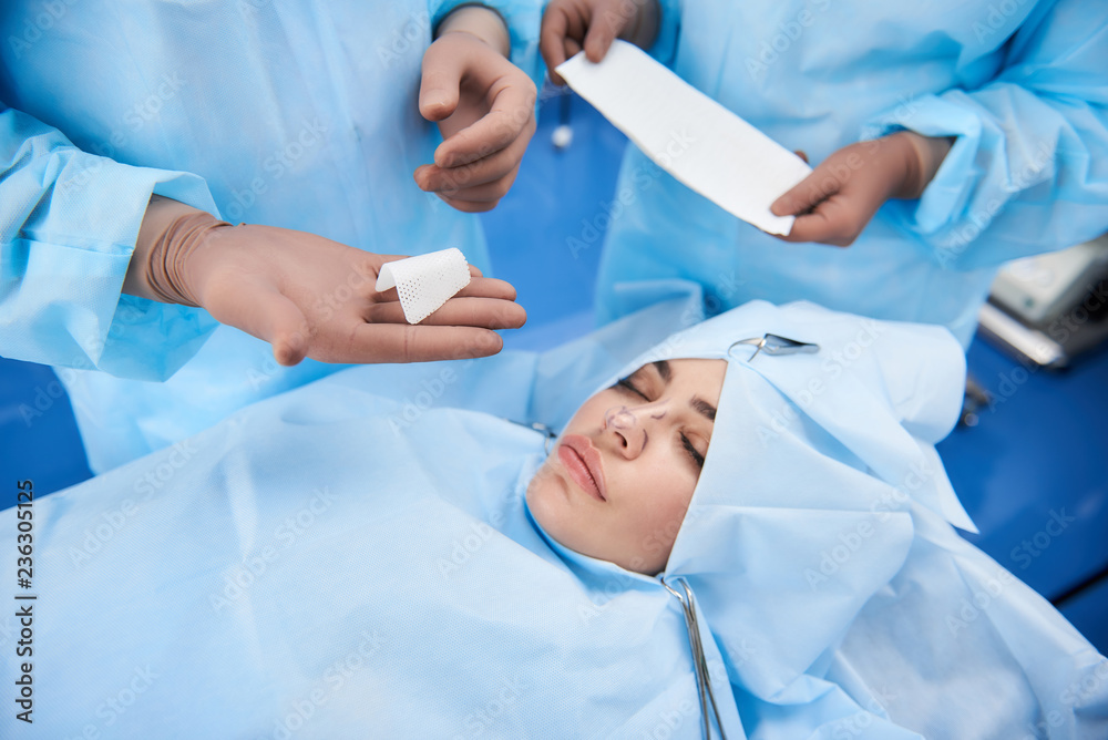 Top view of plastic surgeon preparing bandage for patient after surgery Top view of plastic surgeon preparing bandage for patient after surgery