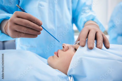 Close up of doctor in rubber gloves holding medical instrument near nose of woman and putting her hand on her head