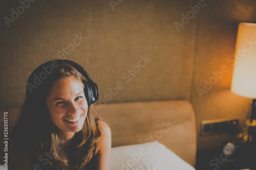 Junge, lachende Frau hört Musik in ihrem Zimmer