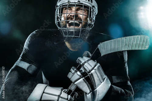 Happy ice hockey player man in the mask and gloves on stadium with stick celebrates victory. Male closeup portrait.