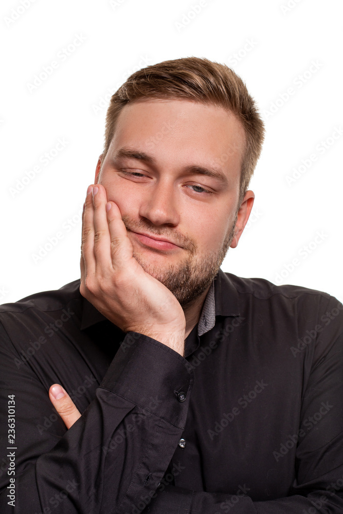 Studio portrait of gloomy european man showing boredom while leaning head on hand and standing over white background. Studio portrait of gloomy european man showing boredom while leaning head on hand and standing over white background.