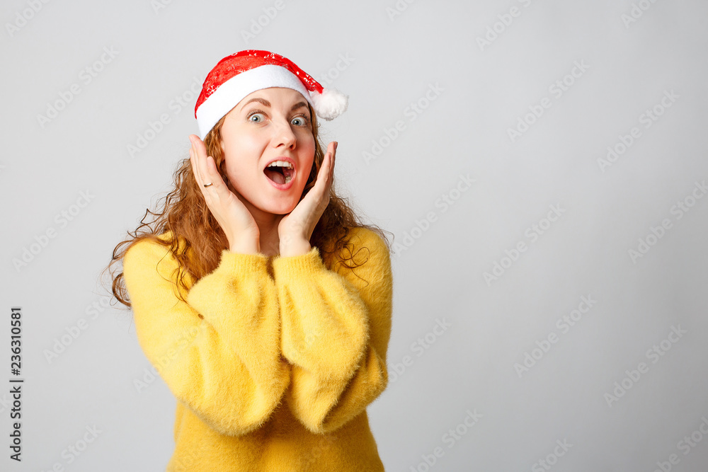 Happy beautiful girl in a yellow sweater, christmas cap on a white background. Happy beautiful girl in a yellow sweater, christmas cap on a white background.