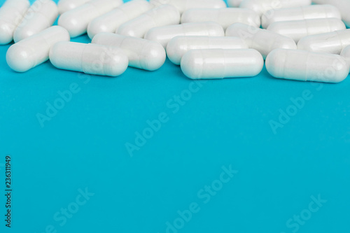 White capsules of medicine lie on a blue background. photo