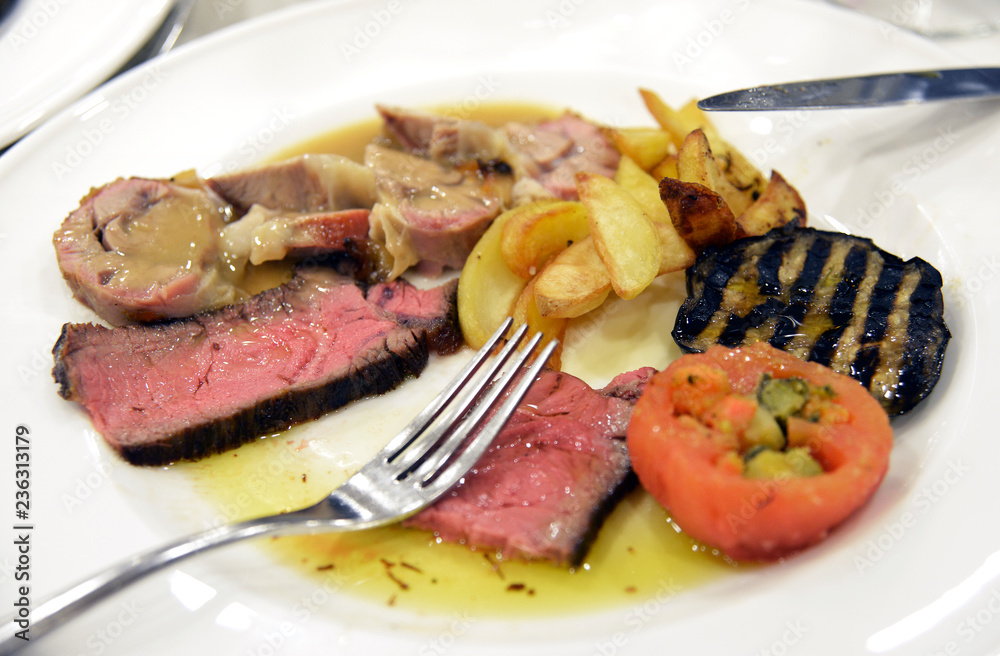 Plate of sliced meat with aubergines tomatoes and potatoes