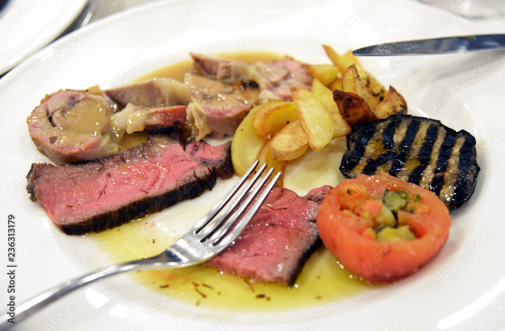 Plate of sliced meat with aubergines tomatoes and potatoes Plate of sliced meat with aubergines tomatoes and potatoes