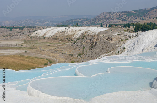 cotton castle in Pamukkale, Turkey. White limestone cliffs with water, against the sky
