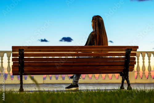 Girl enjoying city view from a bench in sunset sunrise time.