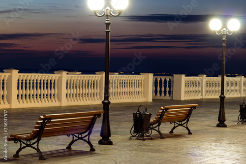 Beautiful evening city with bright lights and a beautiful bench on the road