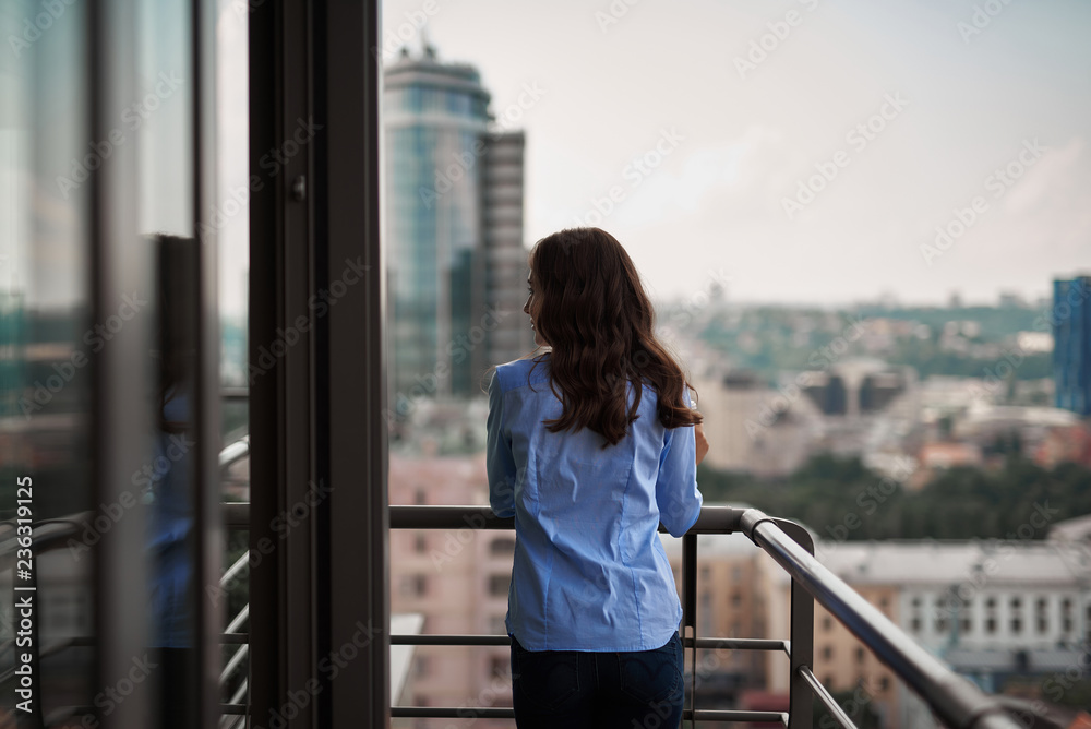 Corporate time-out culture. Back side portrait of young office woman standing on balcony while having breake. Copy space on right Corporate time-out culture. Back side portrait of young office woman standing on balcony while having breake. Copy space on right