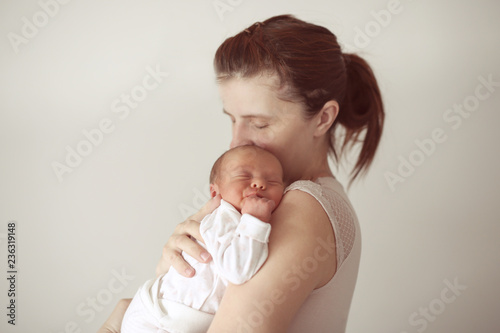 Ordinary mother hugs and kisses newborn baby