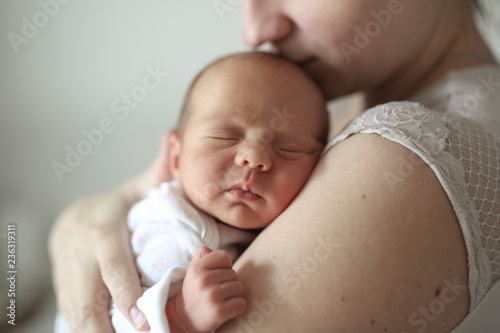Ordinary mother hugs and kisses newborn baby