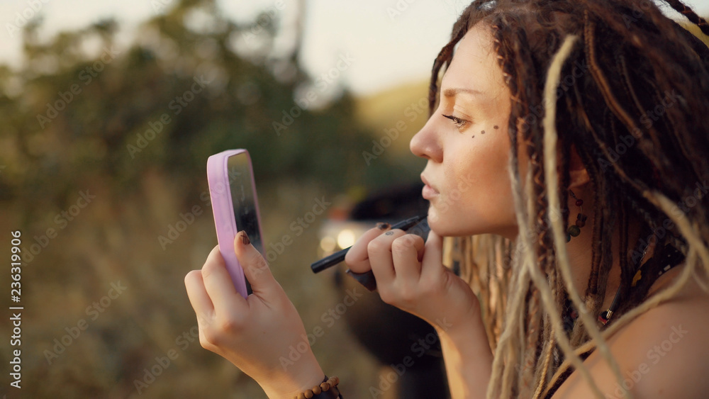 portrait of an attractive hippie woman with dreadlocks in the woods at sunset having good time outdoors