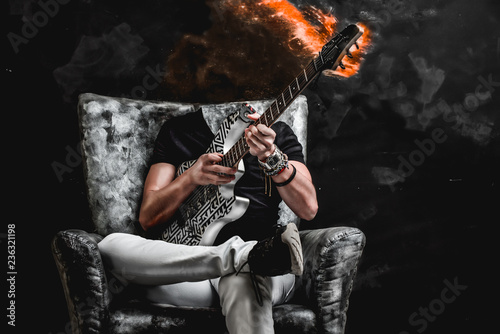 evil, mad guitarist sitting on a black and silver chair, playing the instrument, fire and smoke comes out of the guitar's neck  photo