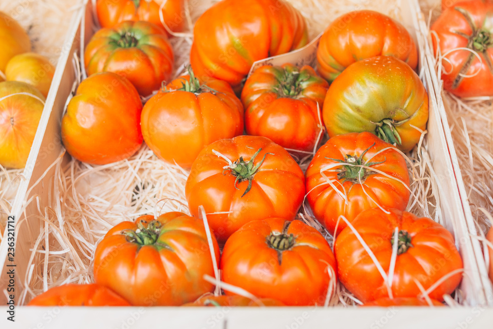 Rich harvest of juicy large tomatoes in a box on the market