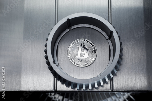 Silver Bitcoin coin lies on the metallic shiny surface 