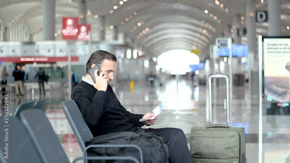 Passenger talking on the phone and checking information on boarding pass Passenger talking on the phone and checking information on boarding pass