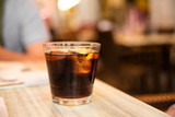 Glass of cola with ice and lemon on the table. Street cafe. Soft focus. Copy space