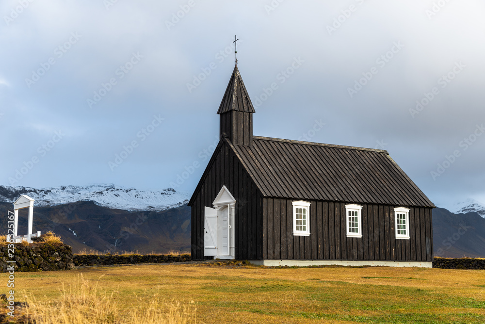 Small Black Wooden Church with Cloudy Mountains in Background in West Iceland on a Rainy Fall Day