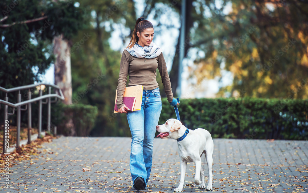 Young woman walks through the park with a dog. Pets and animals concept Young woman walks through the park with a dog. Pets and animals concept