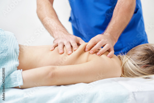 Physiotherapist doing healing treatment on man s back. Therapist wearing blue uniform. Osteopathy. Chiropractic adjustment  patient lying on massage table