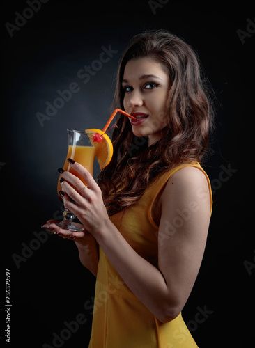 Young beautiful girl in a orange dress with cocktail Tequila Sunrise.