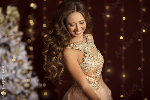 Beautiful happy young girl is wearing fashion golden dress with gift box