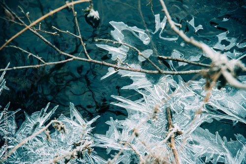 Ice fragments under thin layer of frozen river water. Dark blue natural background