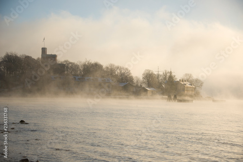 Foggy morning in stockholm harbour, ships and boats in the frosty mist and winter light