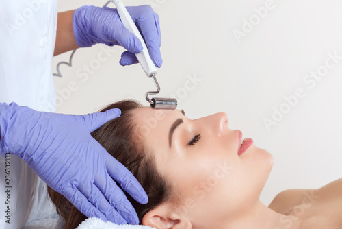 The cosmetologist makes the apparatus a procedure of Microcurrent therapy of a beautiful, young woman in a beauty salon. Cosmetology and professional skin care.